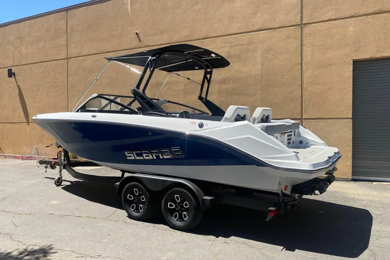 Slide: The Image of 2025 Scarab 235 SE boat on trailer, parked outdoors, featuring sleek design and modern features. - 23