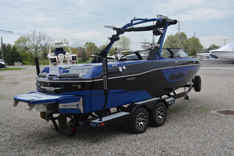 Slide: The Image of 2022 Malibu Wakesetter 23 LSV boat on trailer, blue and black design, parked outdoors. - 2