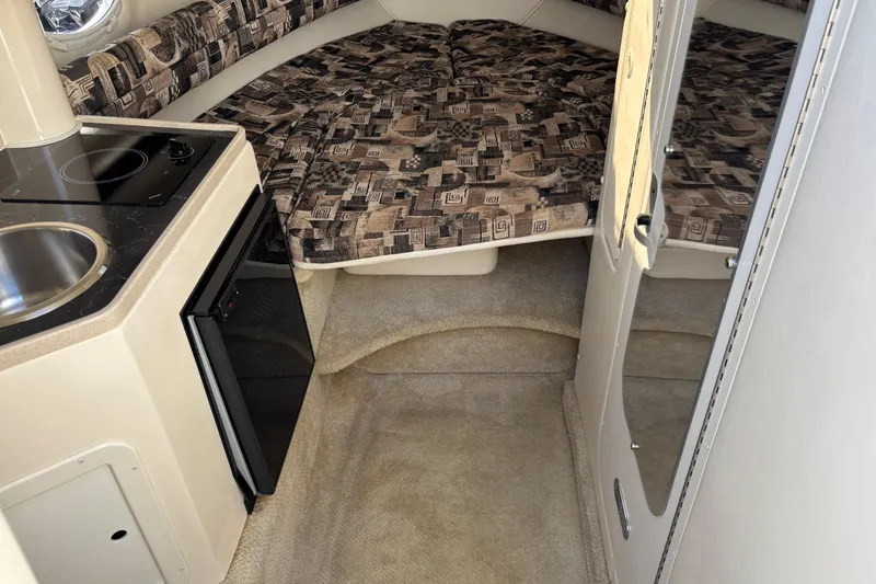 Slide: The Image of 2002 Rinker Fiesta Vee 270 cabin interior with kitchenette and patterned bedding. - 14