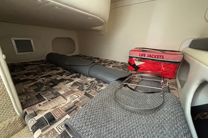 Slide: The Image of 2002 Rinker Fiesta Vee 270 cabin interior with life jackets and rolled mats. - 18