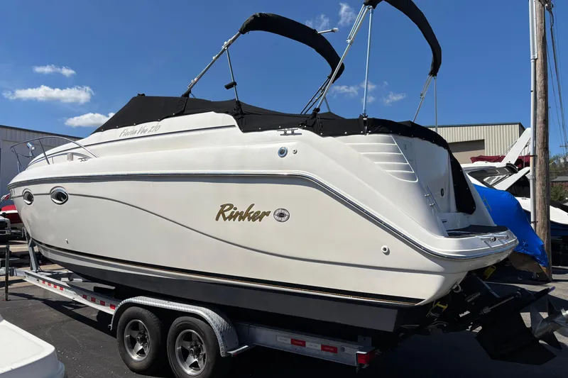 Slide: The Image of 2002 Rinker Fiesta Vee 270 boat on trailer, featuring sleek design and black canopy. - 2
