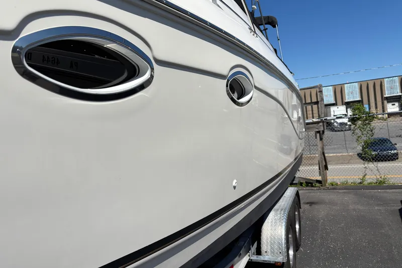 Slide: The Image of 2002 Rinker Fiesta Vee 270 boat side view, parked on a trailer, under clear blue sky. - 4