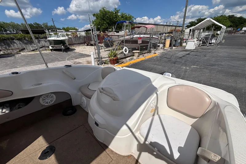 Slide: The Image of 2002 Sea Ray 176 Bow Rider interior with seating, parked in a marina under a clear sky. - 13