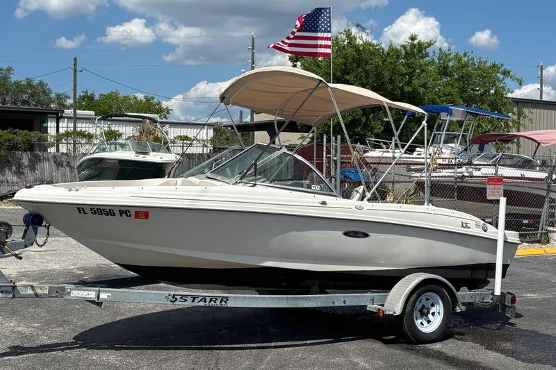 Slide: The Image of 2002 Sea Ray 176 Bow Rider on trailer with American flag, parked outdoors. - 9