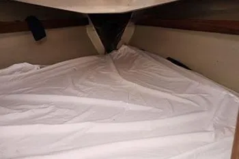 Slide: The Image of Interior view of a 1977 C&C 29 sailboat cabin with white bedding. - 10