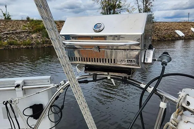 Slide: The Image of Stainless steel Magma grill mounted on a 1977 C&C 29 sailboat, near a calm waterway. - 13