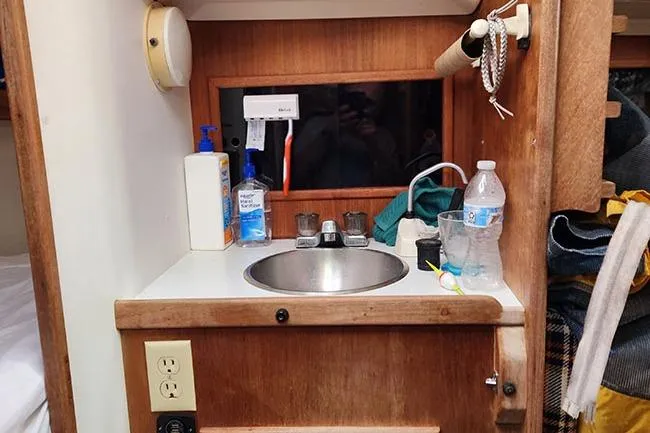 Slide: The Image of Small sink area in a 1977 C&C 29 sailboat cabin with toiletries and a water bottle. - 7