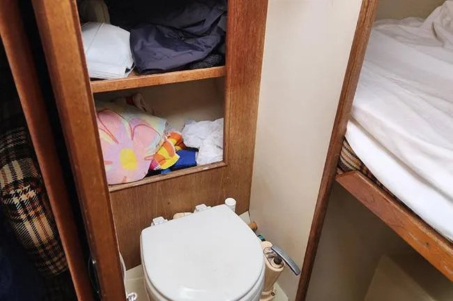 Slide: The Image of Small bathroom in a 1977 C&C 29 sailboat with storage shelves and a toilet. - 8