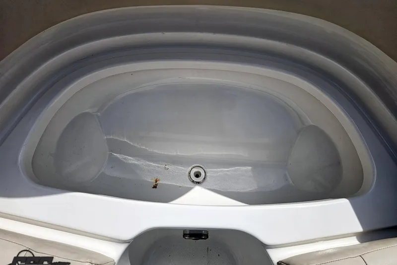 Slide: The Image of 2007 Chaparral 256 SSi boat storage compartment, empty and clean, with visible drain plug. - 77