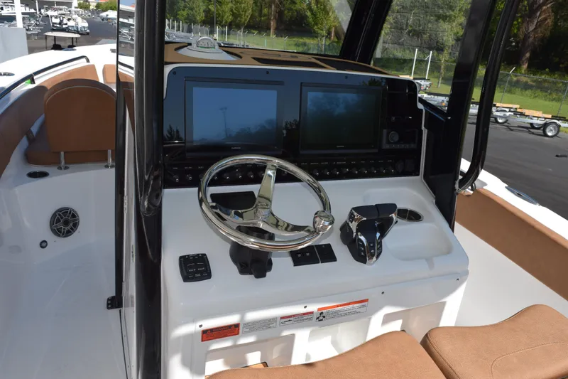 Slide: The Image of 2026 Sea Hunt Ultra 265 SE boat dashboard with steering wheel and navigation screens. - 10