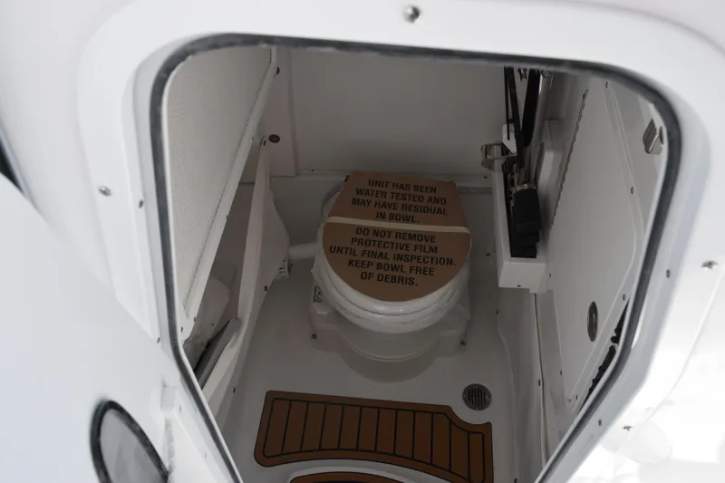 Slide: The Image of Interior of 2026 Sea Hunt Ultra 265 SE boat showing compact marine toilet area. - 15