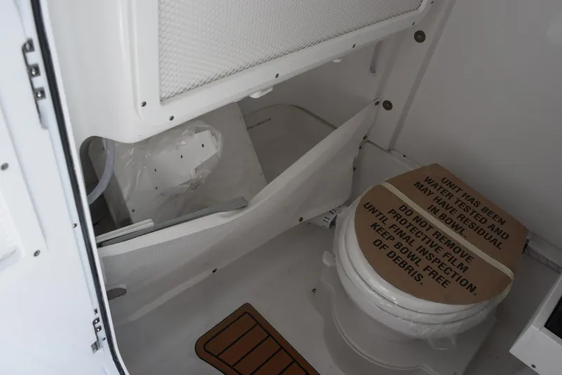 Slide: The Image of Interior of 2026 Sea Hunt Ultra 265 SE boat bathroom with toilet and storage. - 16