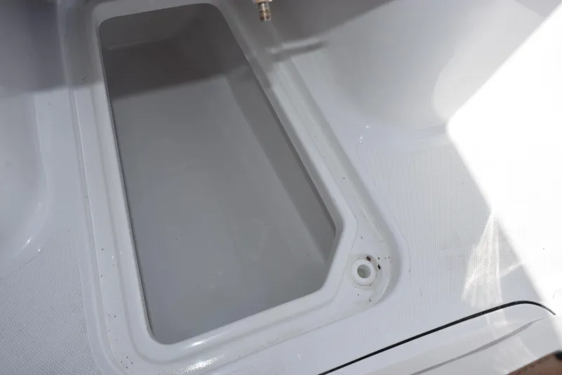 Slide: The Image of Storage compartment of 2026 Sea Hunt Ultra 265 SE boat, featuring a clean, white interior. - 19