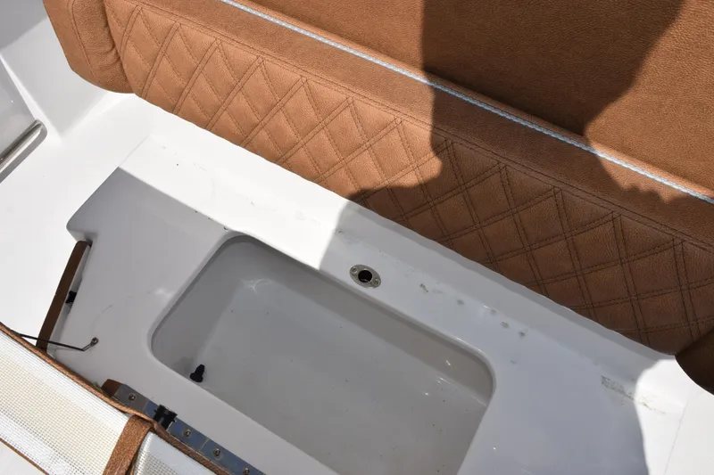 Slide: The Image of 2026 Sea Hunt Ultra 265 SE boat interior with brown cushioned seating and storage compartment. - 22