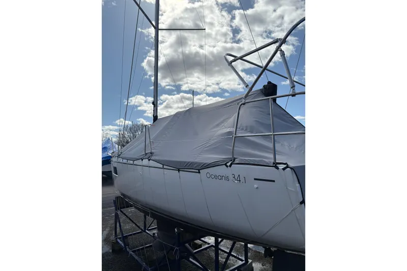 Slide: The Image of 2023 Beneteau Oceanis 34.1 sailboat covered, displayed outdoors under a cloudy sky. - 10