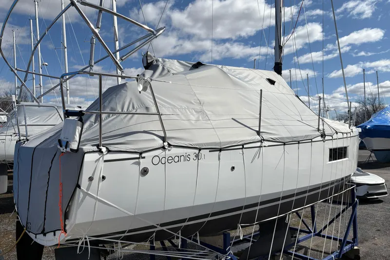 Slide: The Image of 2023 Beneteau Oceanis 34.1 sailboat covered, docked under a clear blue sky. - 6