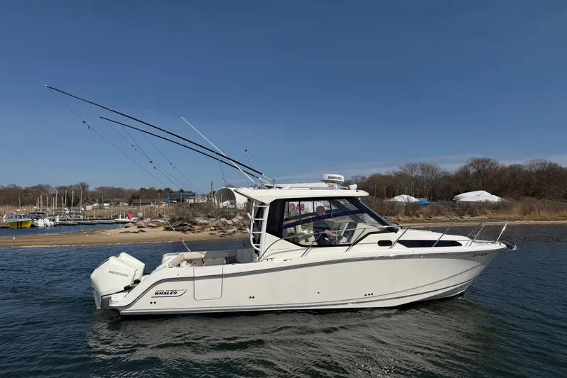 The Image of 2023 Boston Whaler 325 Conquest boat on water near shoreline, clear sky. - 0