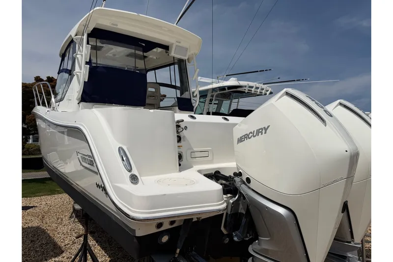 Slide: The Image of 2023 Boston Whaler 325 Conquest boat with dual Mercury engines, docked outdoors. - 2