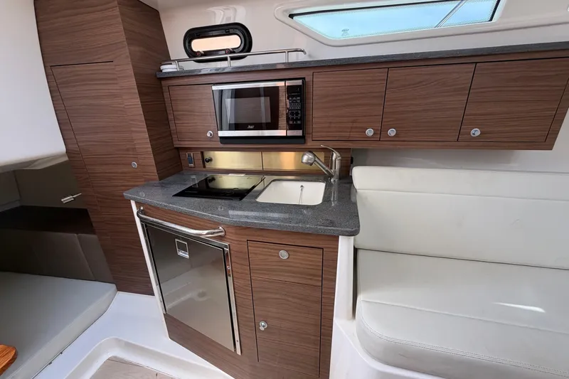 Slide: The Image of 2023 Boston Whaler 325 Conquest interior kitchen with modern appliances and wood cabinetry. - 25