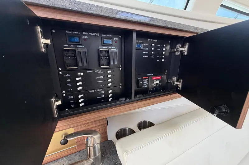 Slide: The Image of Electrical panel inside 2023 Boston Whaler 325 Conquest boat, featuring various power controls. - 26