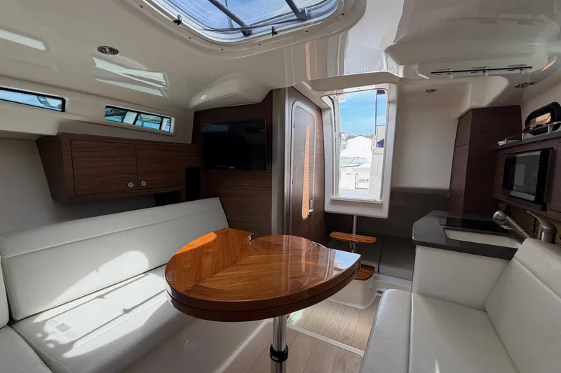Slide: The Image of Interior of 2023 Boston Whaler 325 Conquest, featuring modern seating, table, and kitchenette. - 28