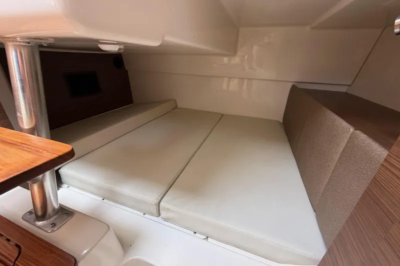 Slide: The Image of 2023 Boston Whaler 325 Conquest cabin interior with cushioned seating and wooden accents. - 31