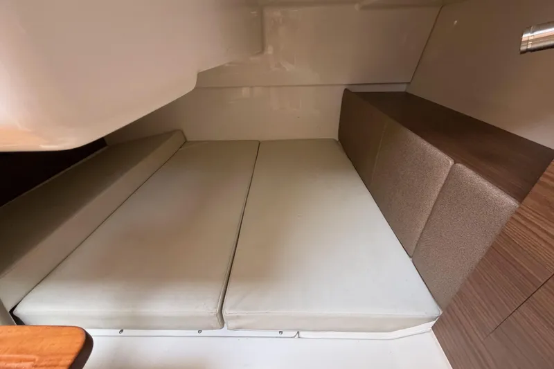 Slide: The Image of 2023 Boston Whaler 325 Conquest cabin interior with cushioned seating and wood accents. - 32