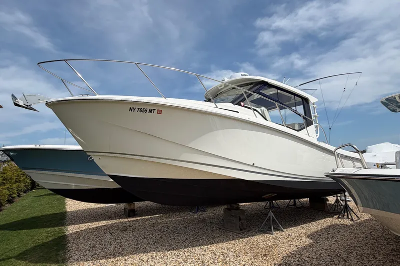 Slide: The Image of 2023 Boston Whaler 325 Conquest boat displayed on gravel under a clear sky. - 38