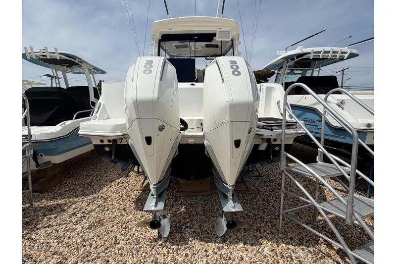 Slide: The Image of 2023 Boston Whaler 325 Conquest with dual outboard engines, displayed on gravel. - 4