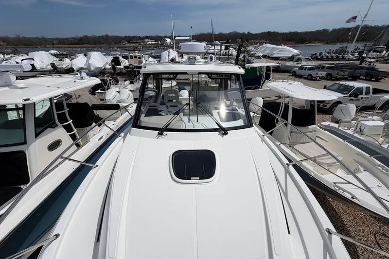 Slide: The Image of 2023 Boston Whaler 325 Conquest boat docked among other vessels at a marina. - 42