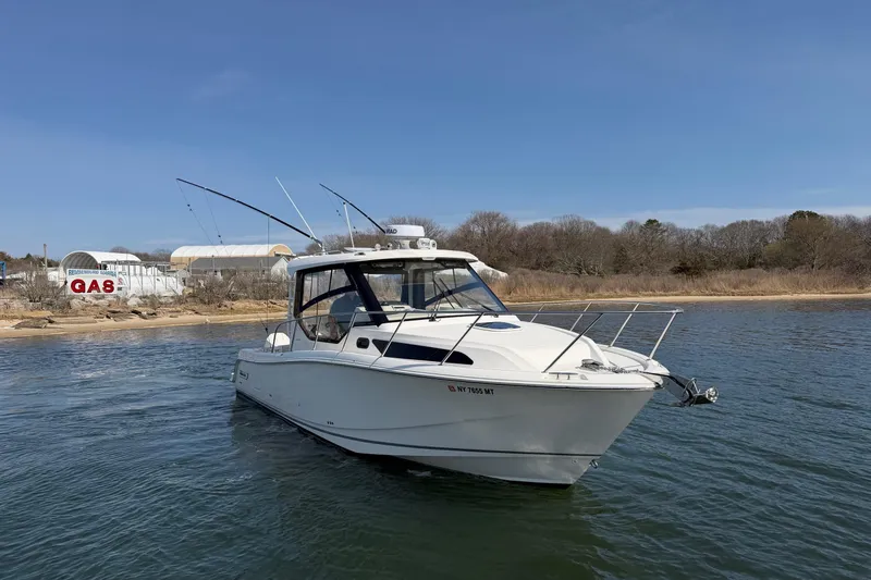 Slide: The Image of 2023 Boston Whaler 325 Conquest boat on water near shoreline with gas station in background. - 45