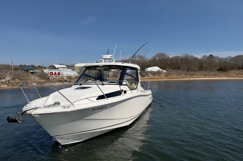 Slide: The Image of 2023 Boston Whaler 325 Conquest boat on calm water near shoreline. - 46