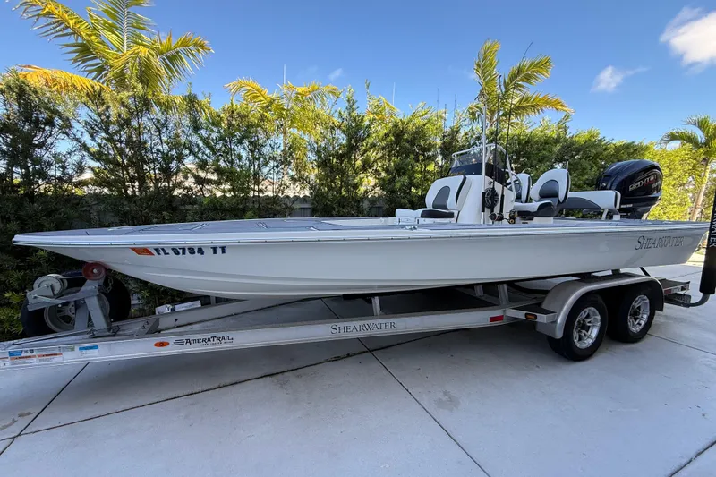 The Image of 2023 ShearWater x22 boat on trailer, surrounded by palm trees. - 1
