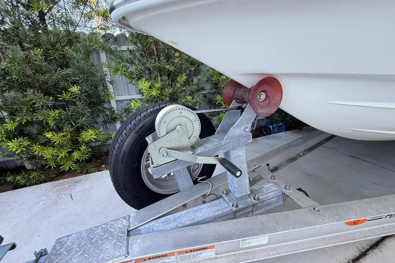 Slide: The Image of Trailer with ShearWater x22 boat, 2023 model, secured on a driveway near greenery. - 15