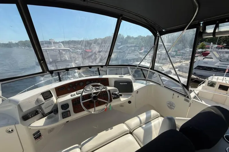 Slide: The Image of 2004 Silverton 43 Motor Yacht helm with marina view, featuring navigation equipment and comfortable seating. - 7