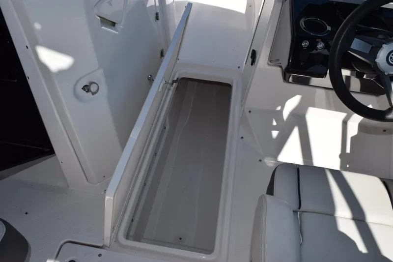 Slide: The Image of 2024 Yamaha Boats AR250 interior storage compartment and steering wheel detail. - 16