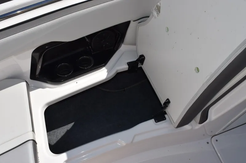 Slide: The Image of 2024 Yamaha Boats AR250 storage compartment with cup holders and carpeted interior. - 18