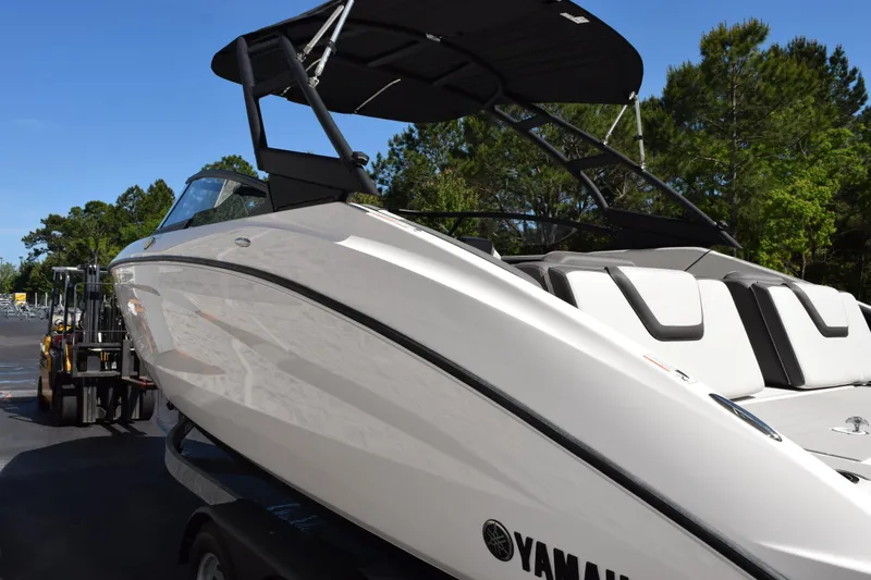 Slide: The Image of 2024 Yamaha Boats AR250, sleek white design, parked outdoors with trees in the background. - 6