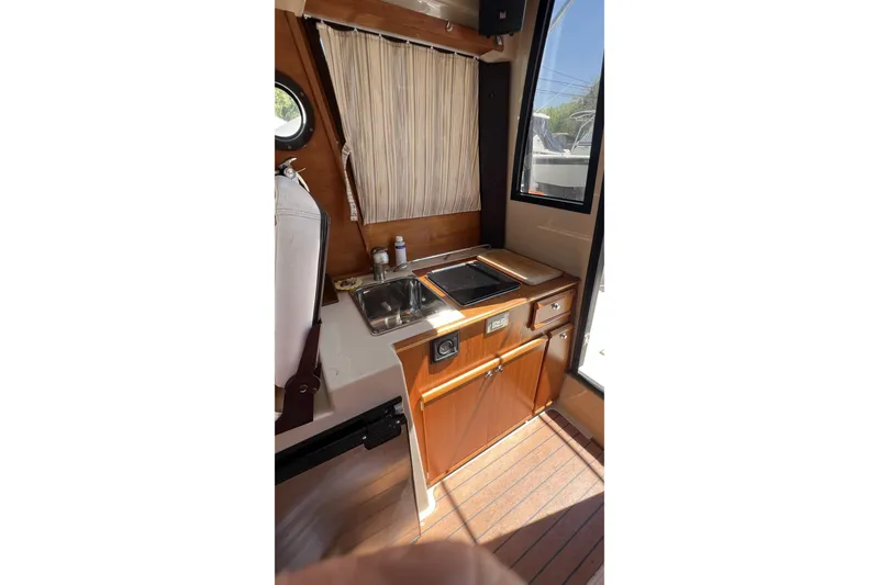Slide: The Image of 2018 Ranger Tugs R-23 interior with compact kitchen, featuring sink and stove. - 14