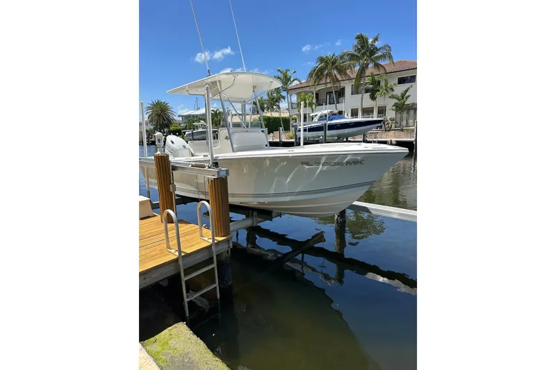 The Image of 2004 Regulator 21 Forward Seating boat docked by waterfront homes, clear blue sky. - 0