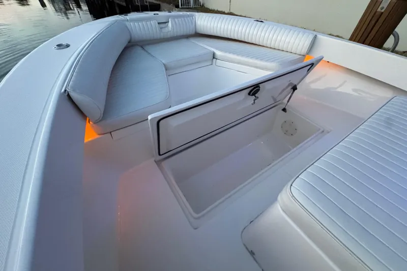 Slide: The Image of 2004 Regulator 21 Forward Seating boat interior with open storage compartment and cushioned seats. - 14