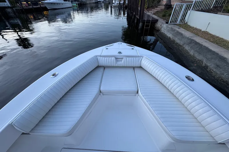 Slide: The Image of 2004 Regulator 21 Forward Seating boat with white cushioned seats, docked by calm waters. - 16