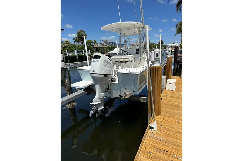 Slide: The Image of 2004 Regulator 21 Forward Seating boat interior with Suzuki engine, docked by the water. - 2