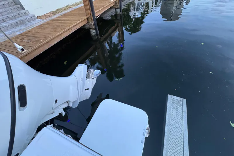 Slide: The Image of Outboard motor of 2004 Regulator 21 Forward Seating boat near wooden dock. - 3