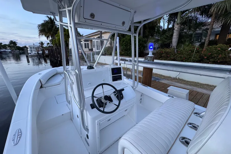 Slide: The Image of 2004 Regulator 21 Forward Seating boat docked by waterfront homes, featuring sleek white interior. - 8
