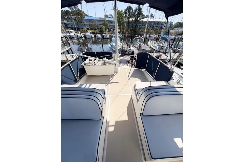 Slide: The Image of Flybridge view of 1991 Grand Banks 36 Classic yacht, featuring cushioned seating and marina backdrop. - 11