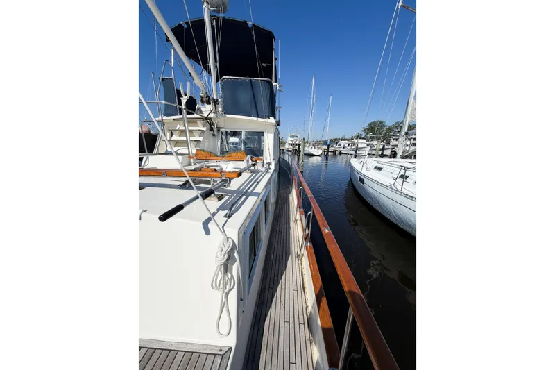 Slide: The Image of Grand Banks 36 Classic yacht docked at marina, showcasing deck and railing, under clear blue sky. - 8