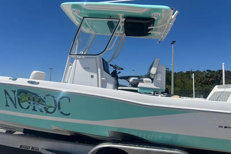 Slide: The Image of 2021 Caymas 28 HB boat with turquoise accents on a trailer under clear blue sky. - 2