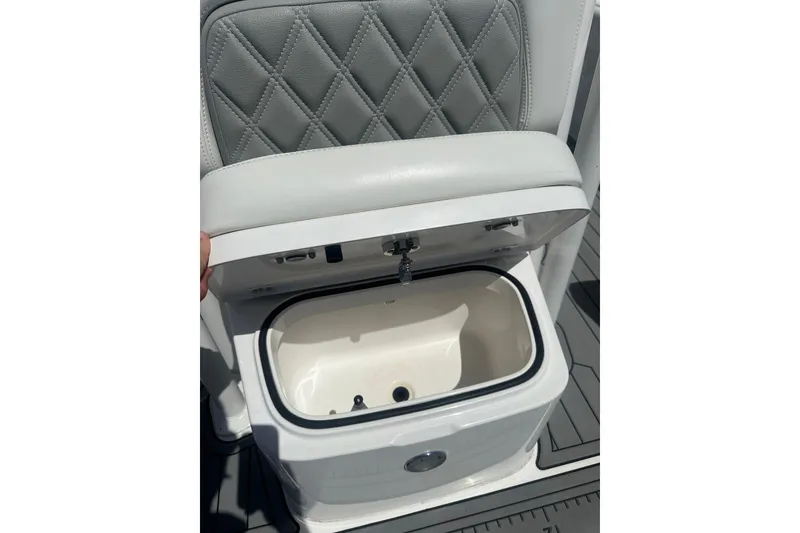 Slide: The Image of 2021 Caymas 28 HB boat seat with storage compartment open, featuring diamond-stitched upholstery. - 26