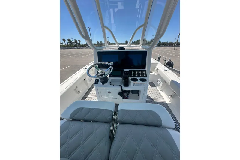 Slide: The Image of 2021 Caymas 28 HB boat helm with steering wheel, controls, and seating in a parking lot. - 9